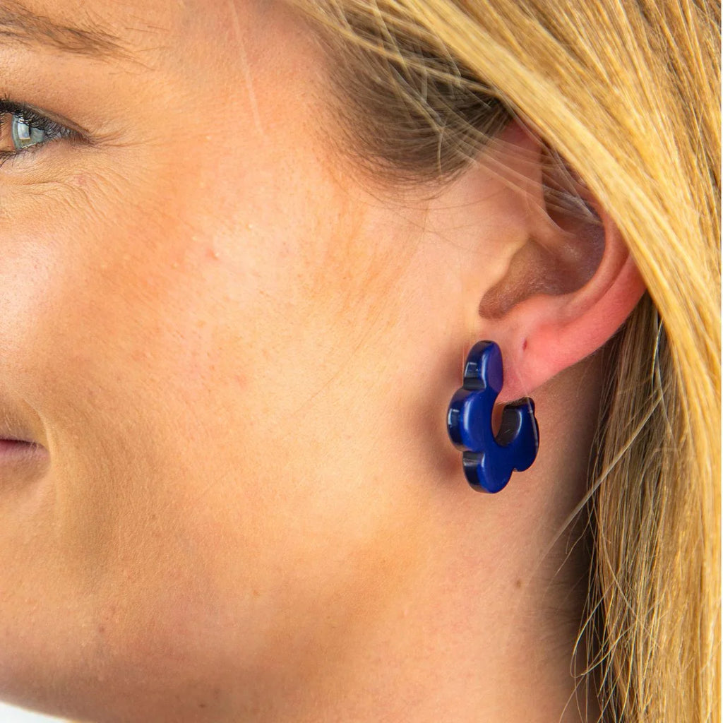 Close-up of a person wearing blue puzzle piece earrings.