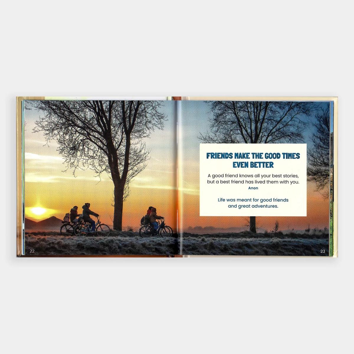Open book showing a sunset scene with two people on bicycles and a motivational quote.
