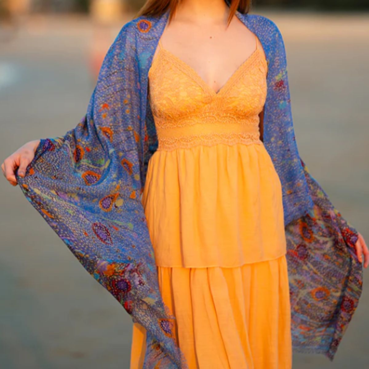 Woman wearing a yellow dress with a blue patterned shawl over her shoulders.