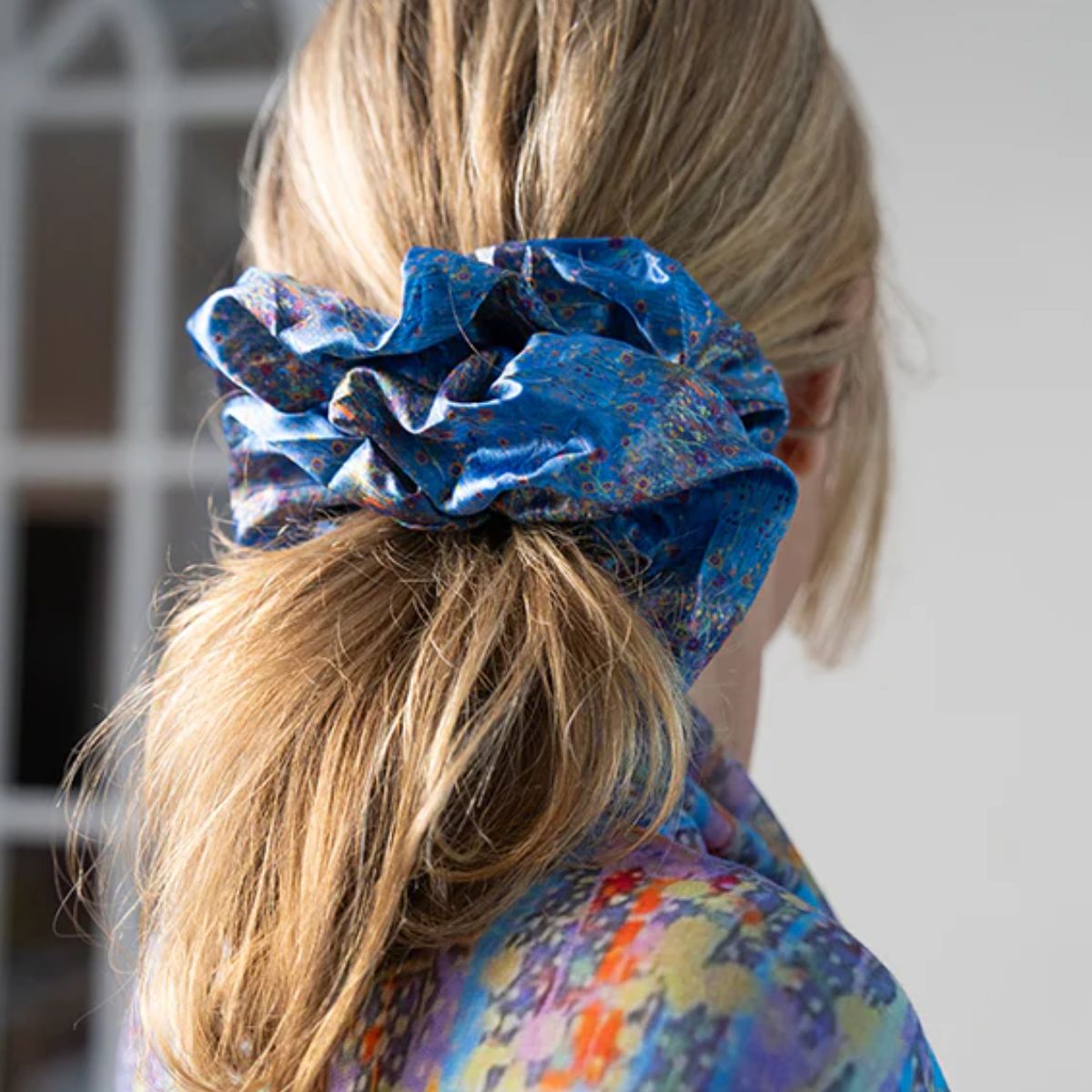 Blue scrunchie on a person's hair with a blurred background