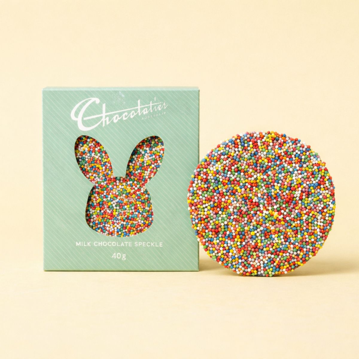 Milk chocolate speckle bar with a green box on a beige background