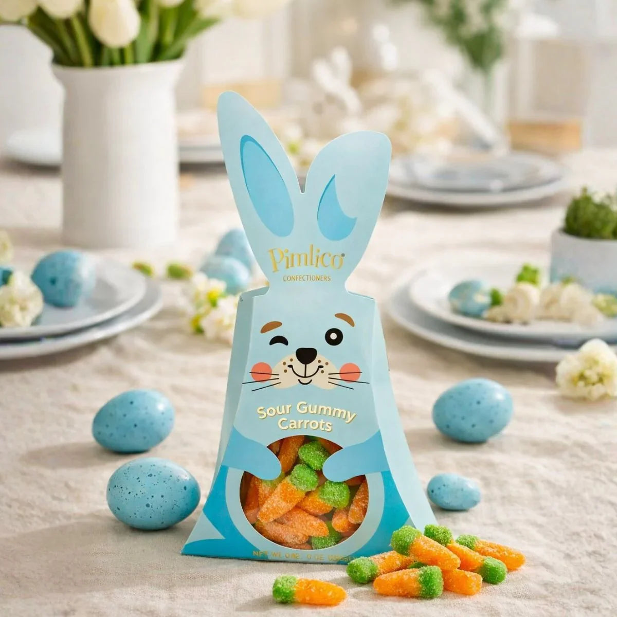 Bunny-shaped package of Sour Gummy Carrots on a table with Easter decorations
