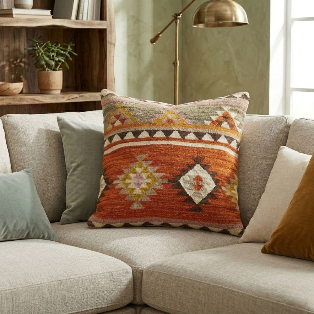 Decorative pillow with geometric pattern on a beige sofa in a living room setting.