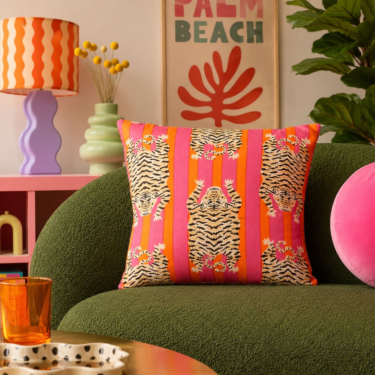 Decorative pillow with tiger design on a green couch in a colorful living room.