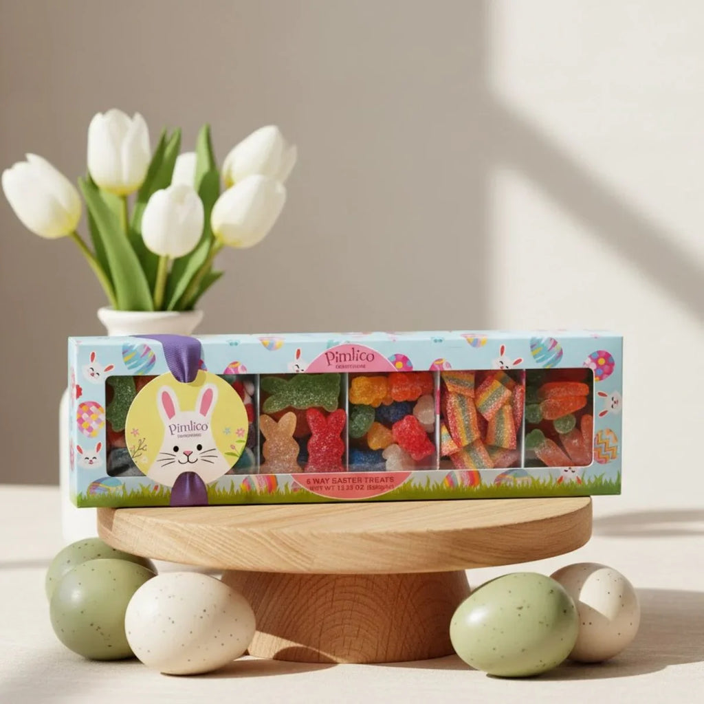 Box of colorful gummy candies on a wooden stand with white tulips and Easter eggs in the background.