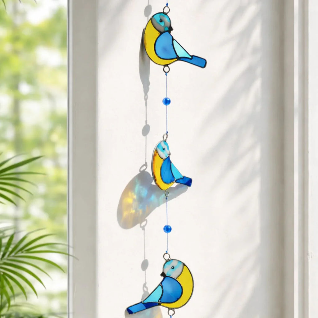 Decorative hanging with blue and yellow bird shapes on a white curtain background