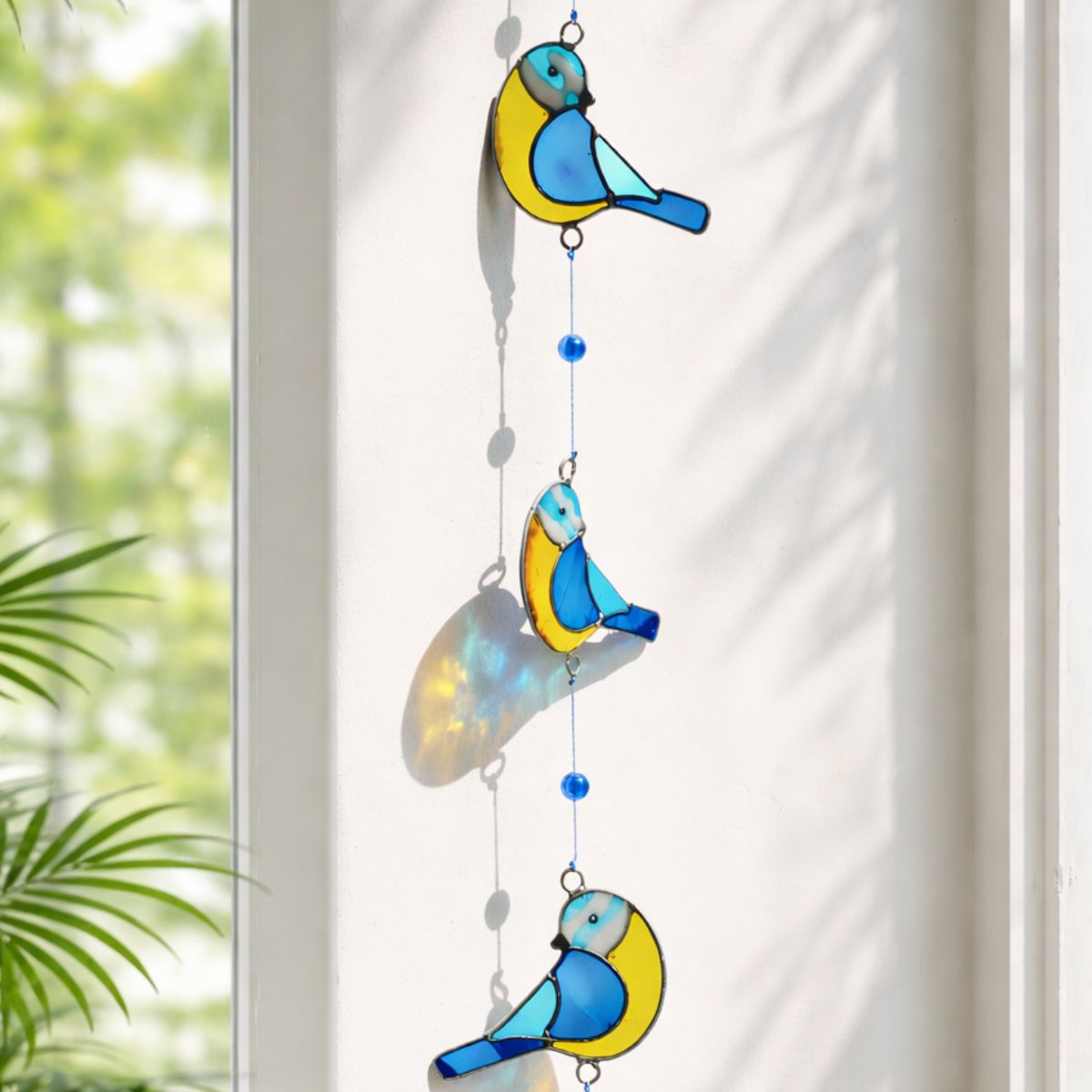 Decorative hanging with blue and yellow bird shapes on a white curtain background