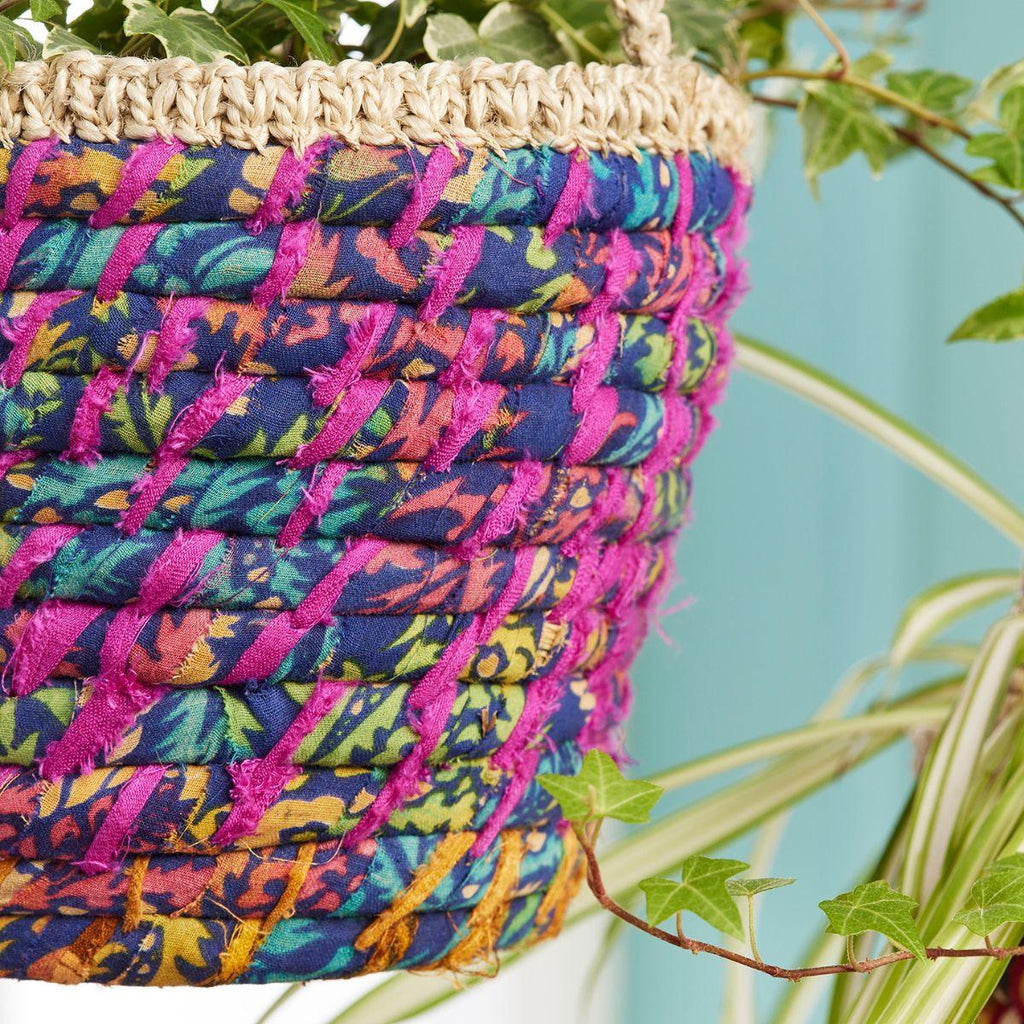 Colorful woven basket with a natural handle against a green plant background