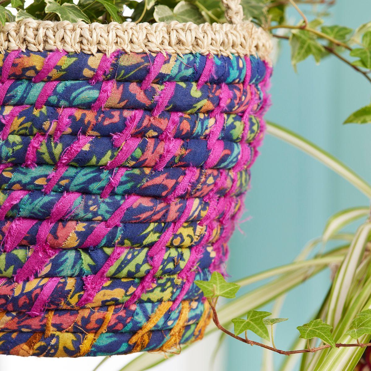 Colorful woven basket with a natural handle against a green plant background