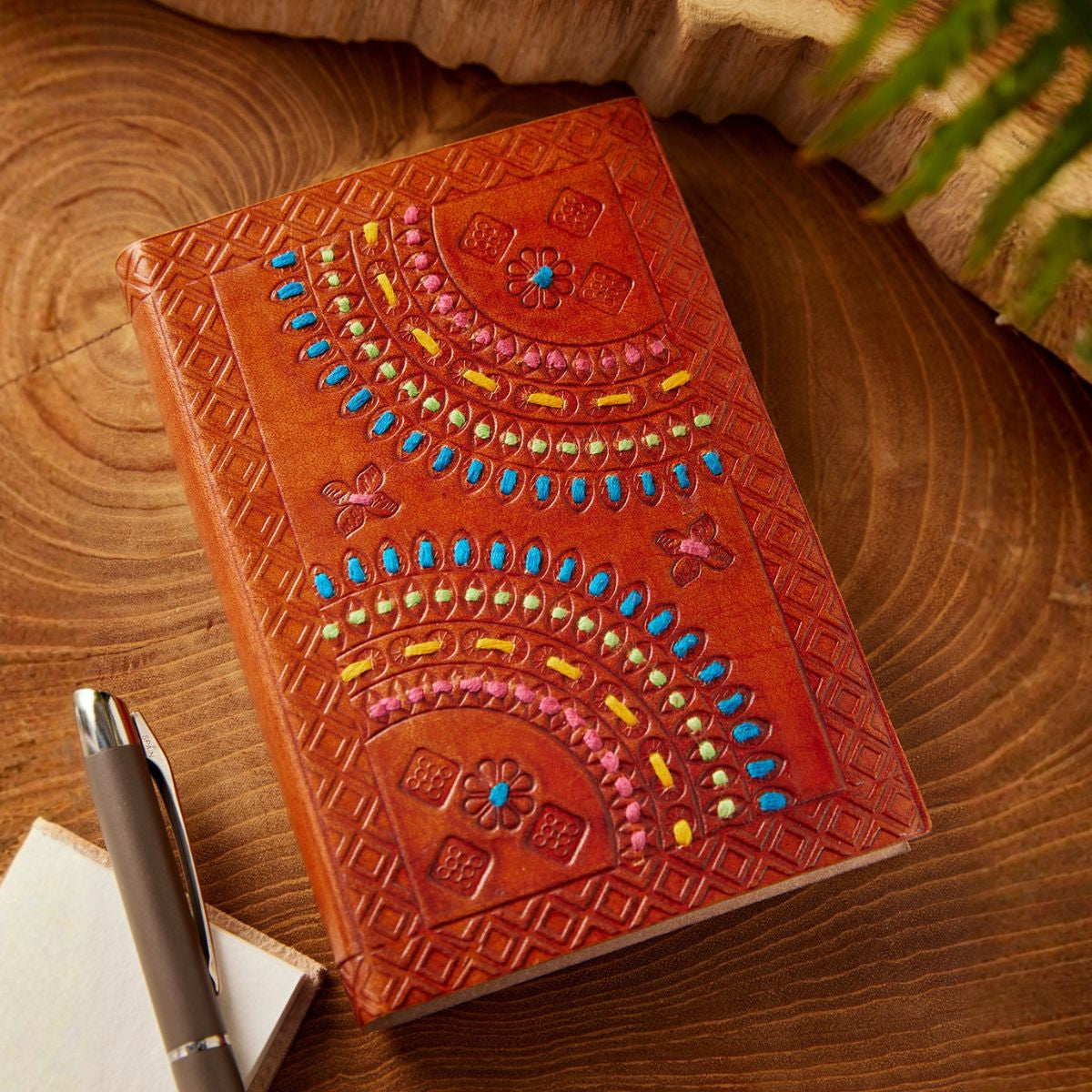 Decorative leather notebook with colorful patterns on a wooden surface