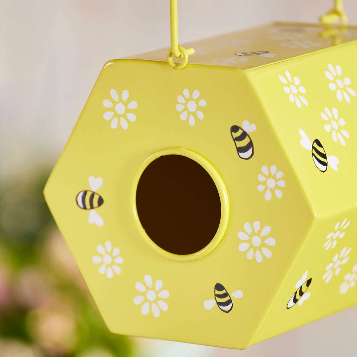 Yellow bee house with bee and flower patterns on a blurred background