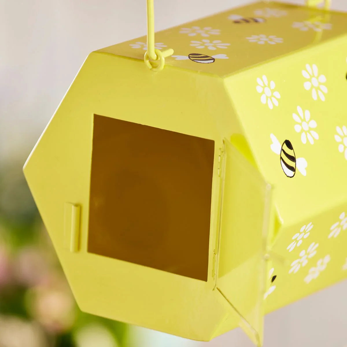 Yellow bee house with floral and bee designs on a blurred natural background
