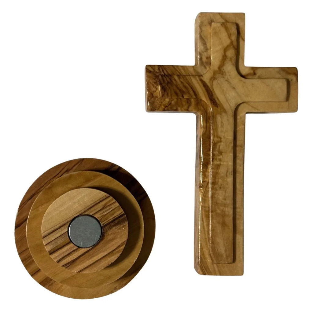 Wooden cross and circular object with central magnet on a white background