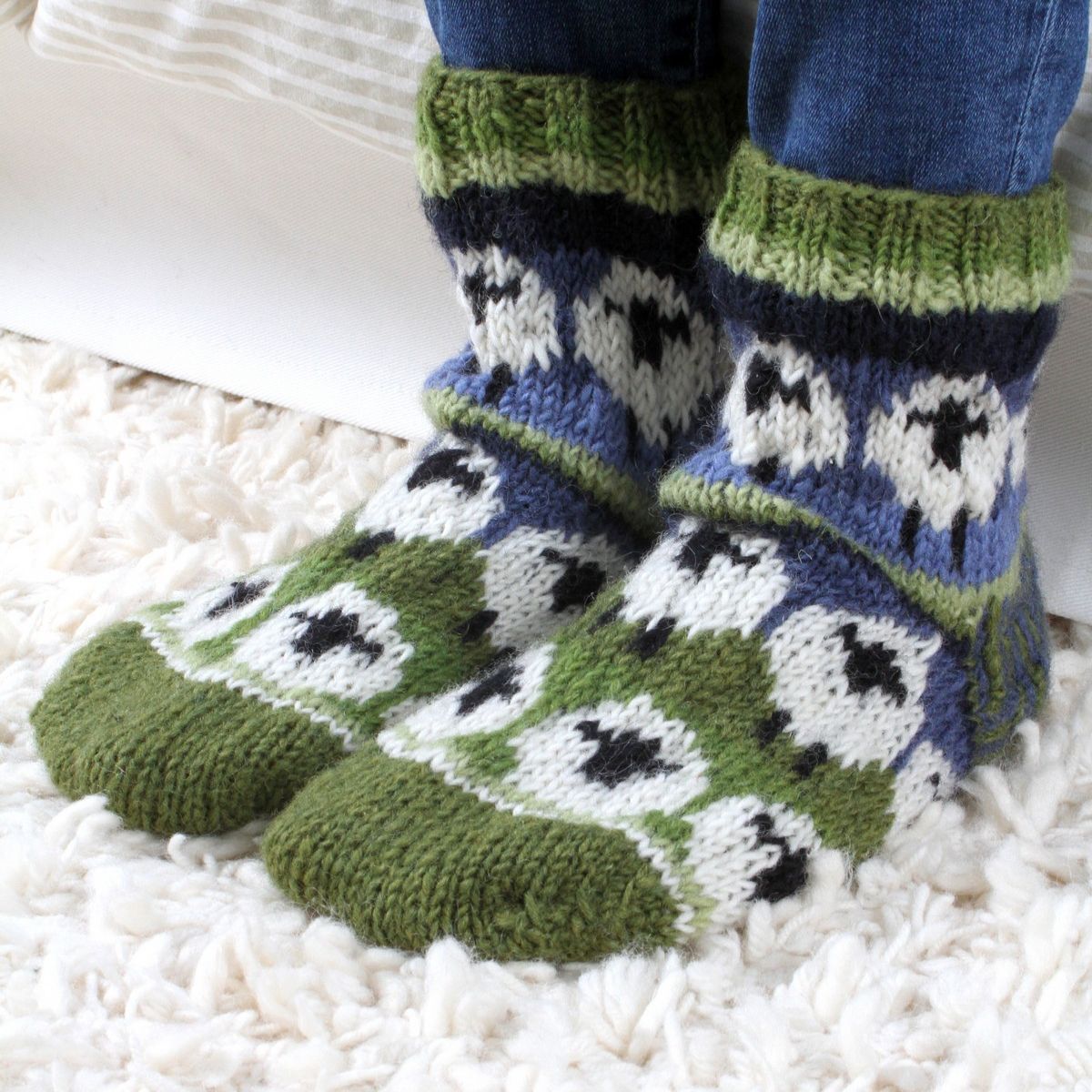 Knitted socks with sheep pattern worn by a person on a white carpet