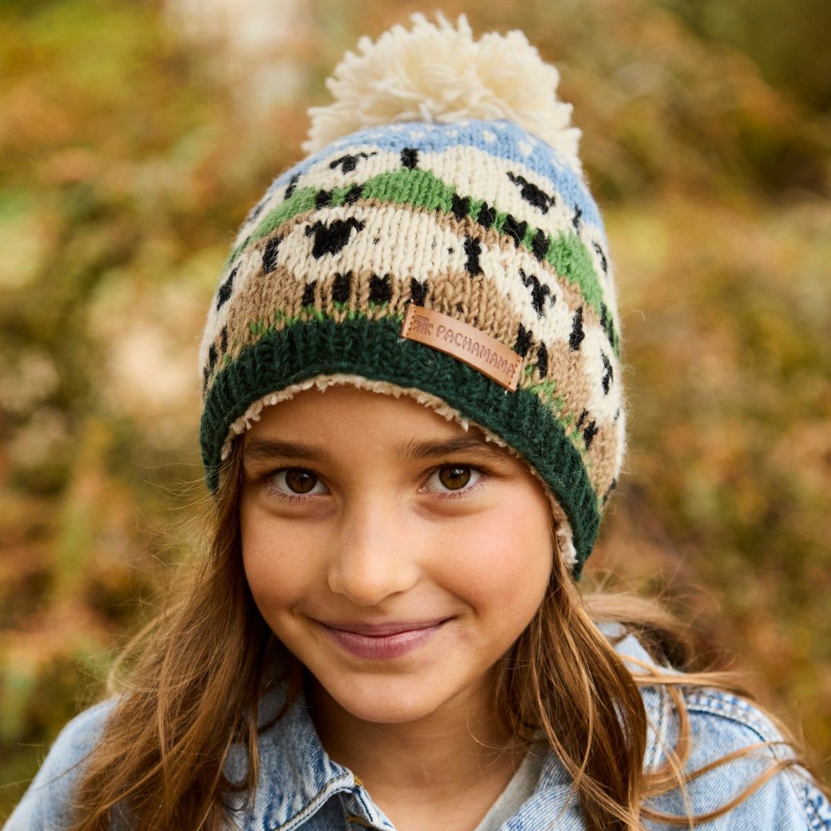 Young girl wearing a patterned knit hat with a pom-pom in an outdoor setting