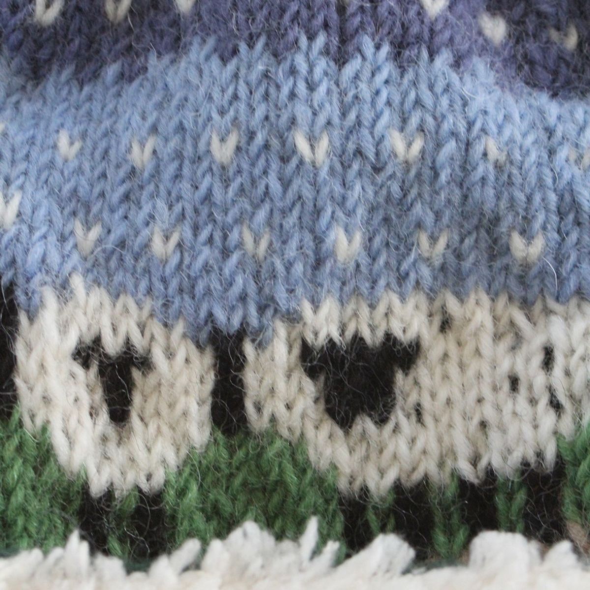 Knitted fabric with sheep pattern in blue, white, and green colors.