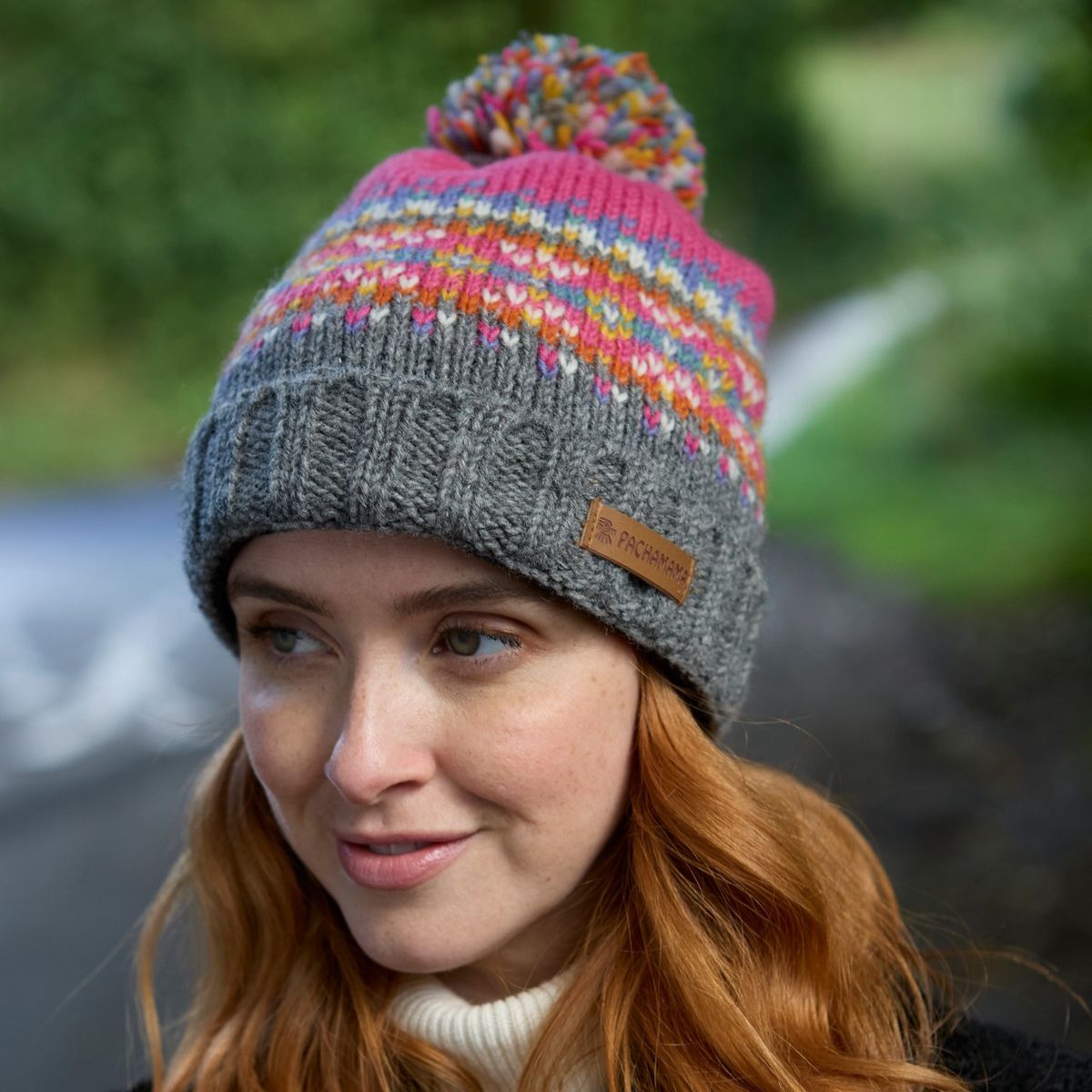 Woman wearing a colorful knit beanie with a brand label, outdoors.