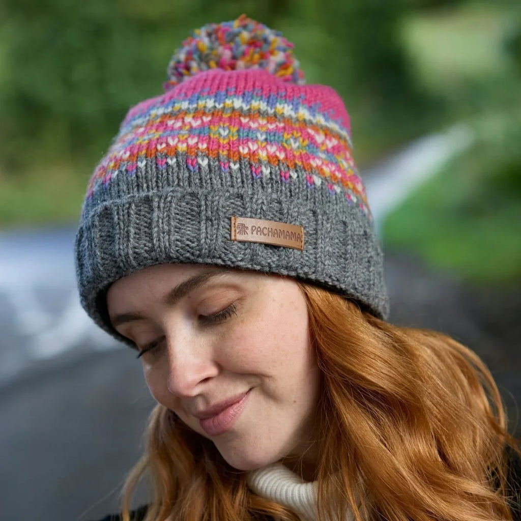 Person wearing a colorful knit beanie with a brand label, outdoors.