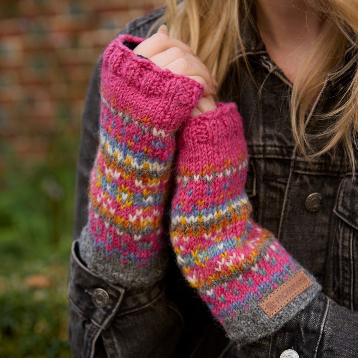 Person wearing colorful knitted fingerless gloves with a blurred background