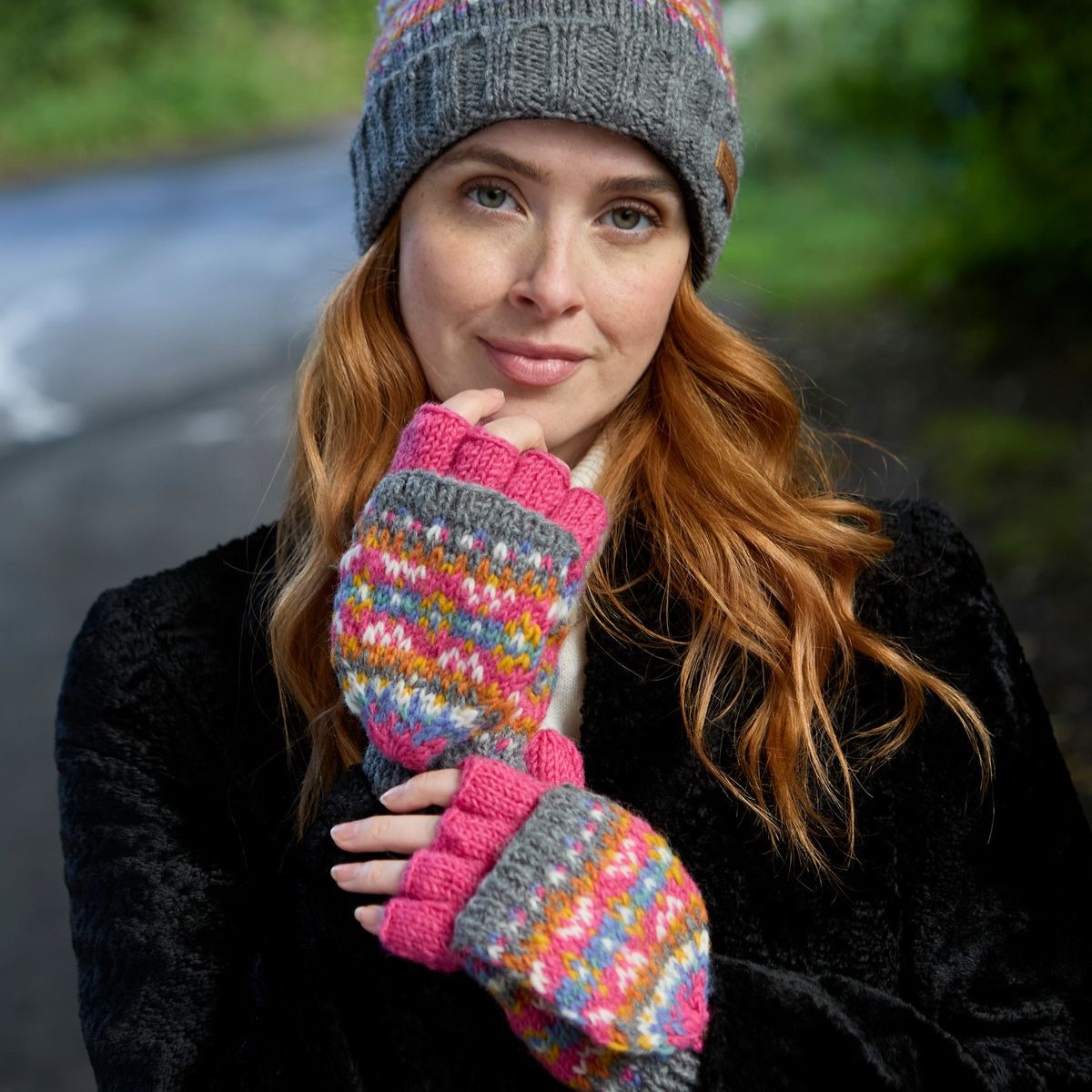 Woman wearing a colorful knitted hat and mittens outdoors