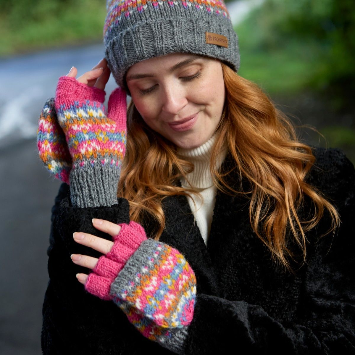 Woman wearing colorful knitted gloves and a hat with a blurred background