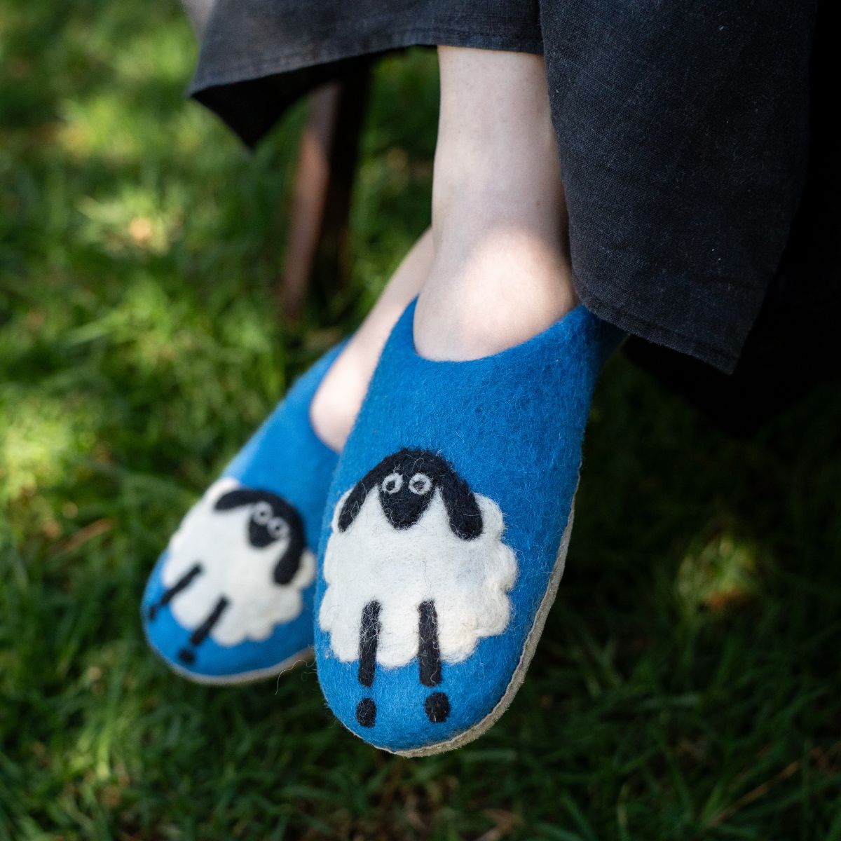 Blue slippers with sheep design worn on grass