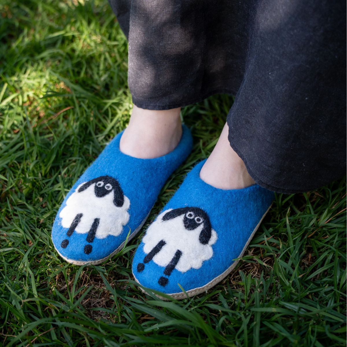 Blue slippers with sheep design worn on grass