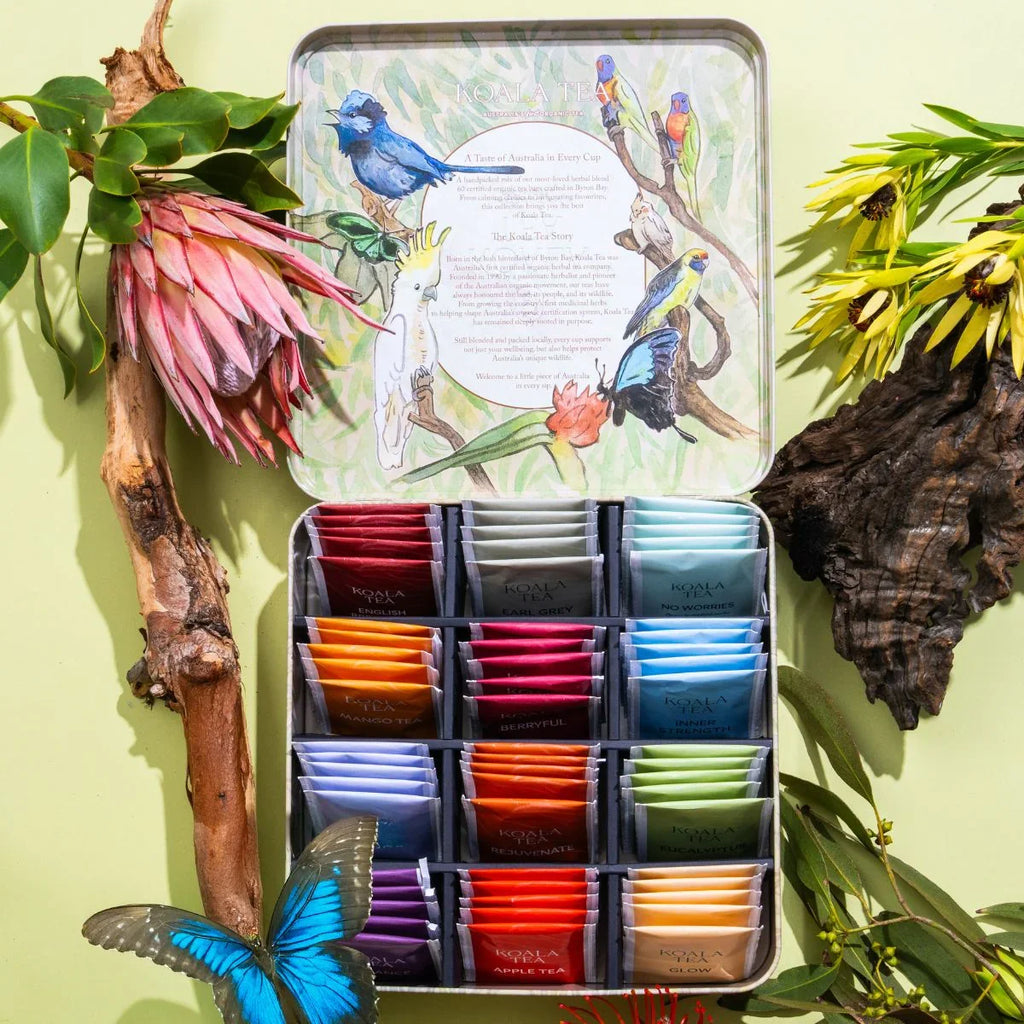 Assorted tea bags in a decorative tin with nature-themed design on a green background