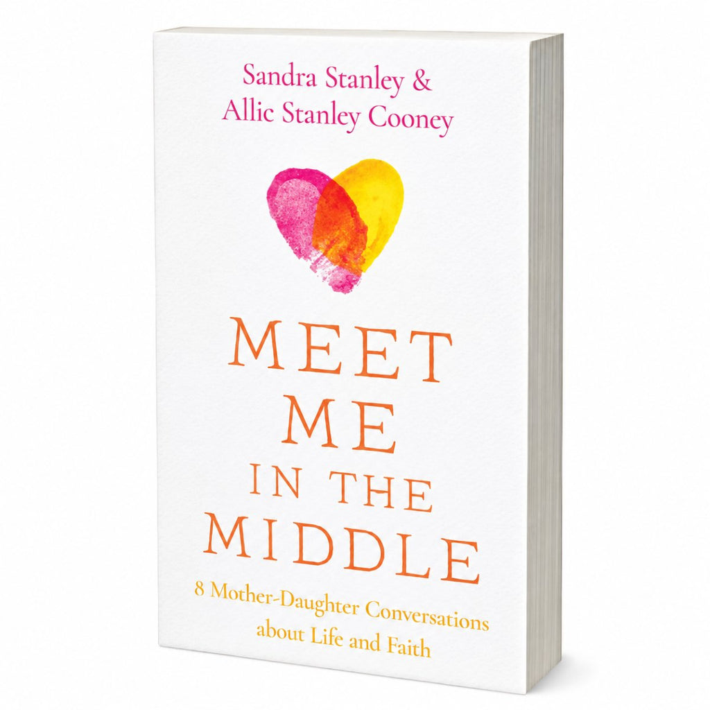 Book cover for 'Meet Me in the Middle' by Sandra Stanley & Allie Stanley Cooney, featuring a white background with a pink and yellow heart graphic and orange title text.