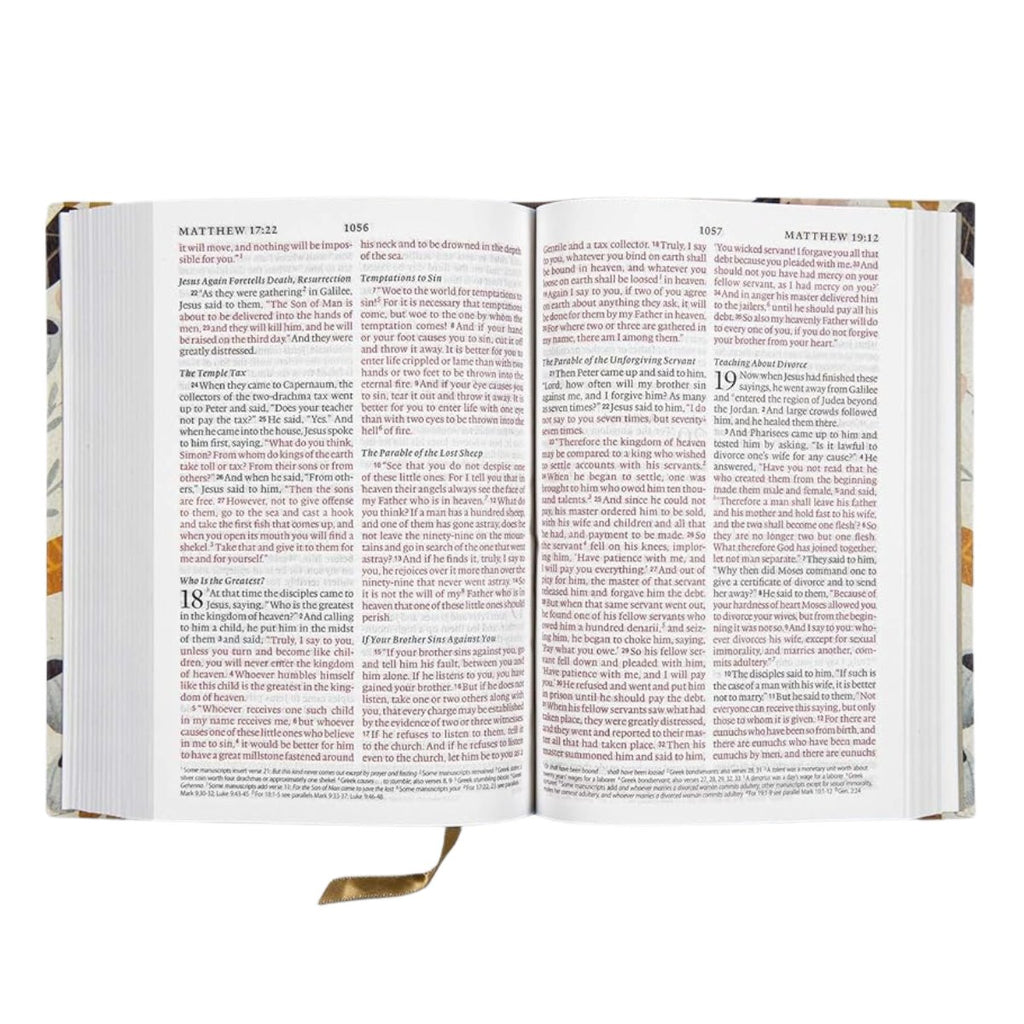 An open Bible showing two spread pages with printed text, photographed against a plain white background. The book has a decorative multicolor floral pattern on the cover and a gold ribbon bookmark hanging from the bottom margin.