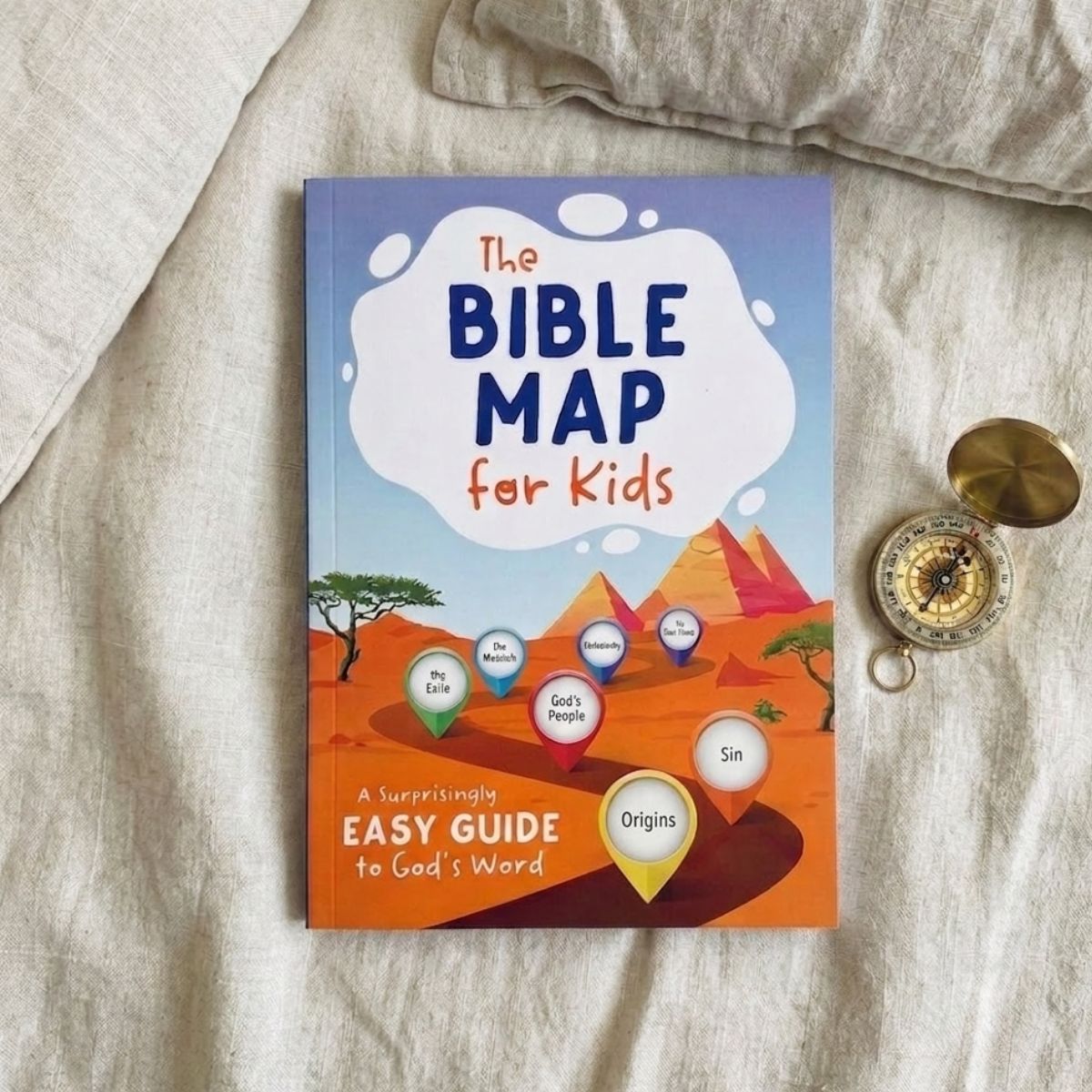 Book titled 'The Bible Map for Kids' on a textured surface with a compass.