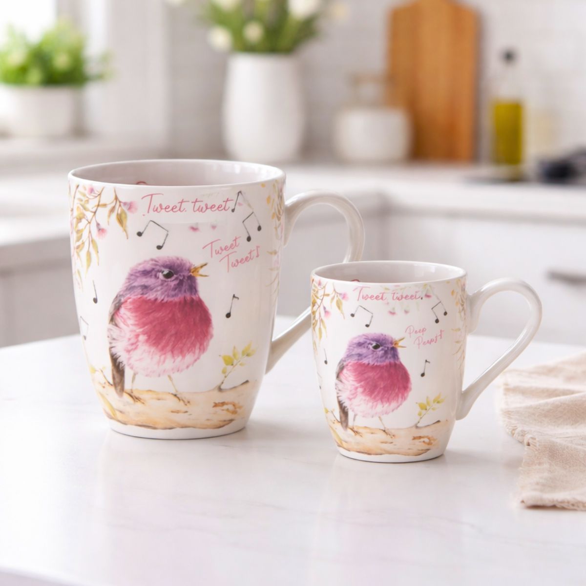 Two ceramic mugs with bird designs on a kitchen counter.