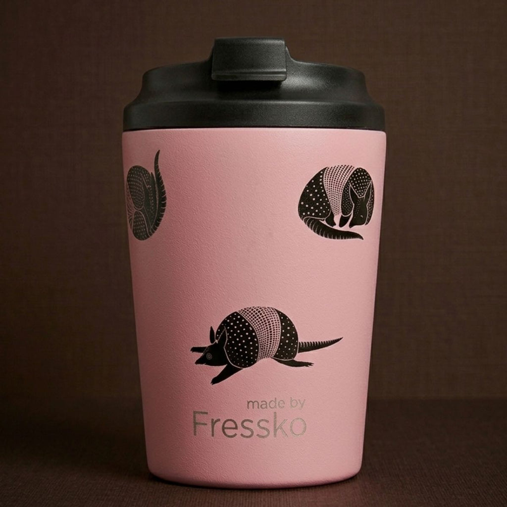 Pink tumbler with black armadillo design and 'made by Fressko' text on a brown background
