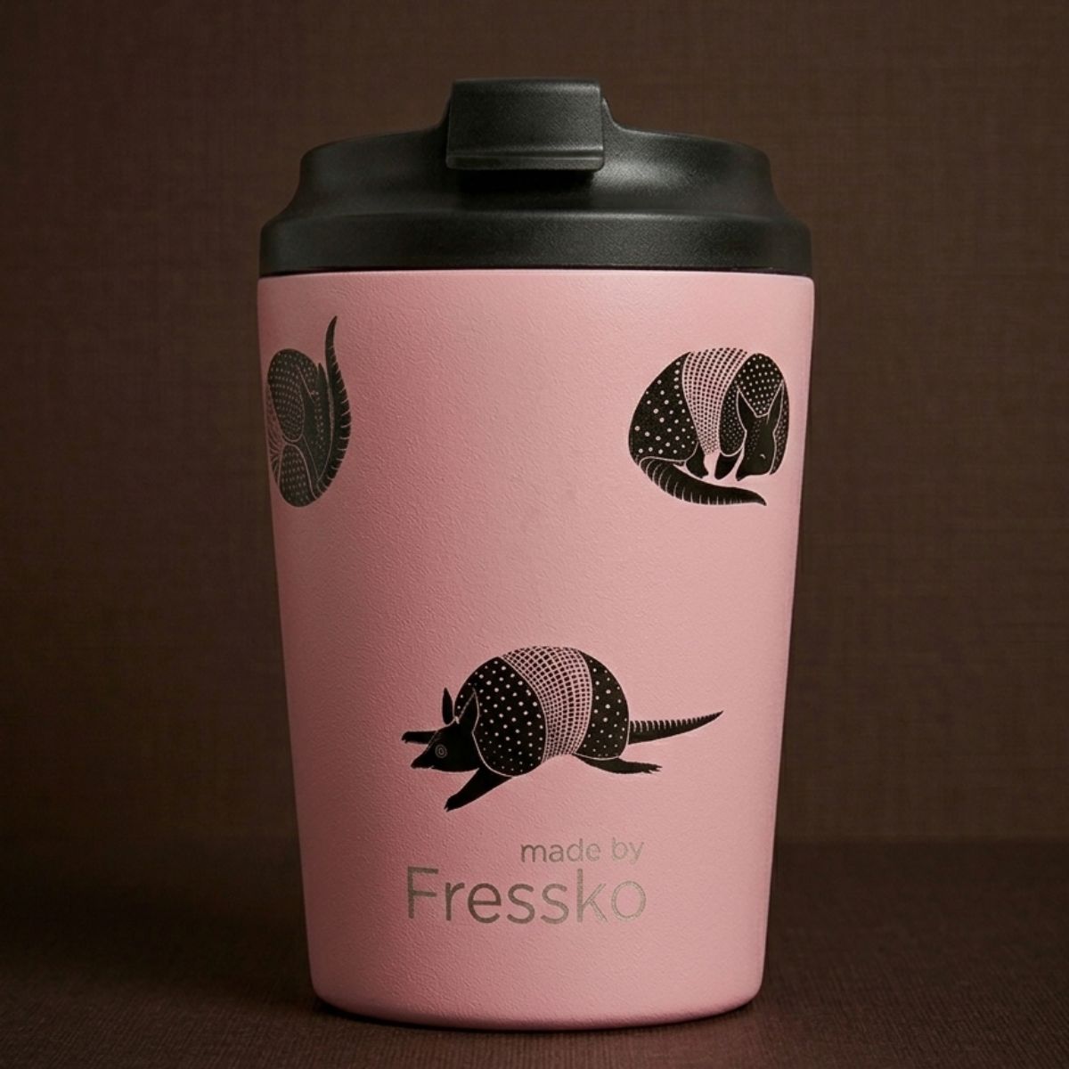 Pink tumbler with black armadillo design and 'made by Fressko' text on a brown background