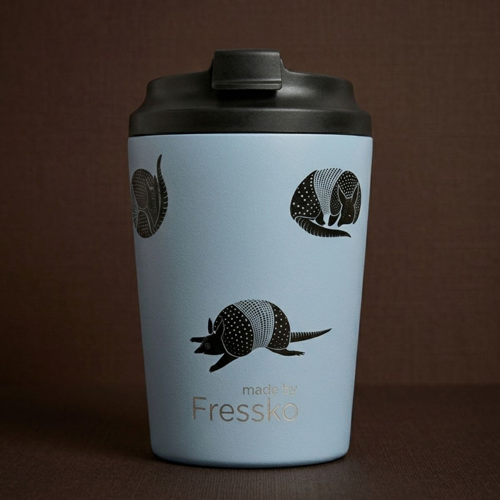 Light blue mug with armadillo illustrations and 'made by Fressko' text on a brown background
