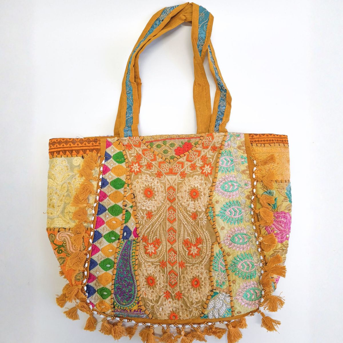 Colorful embroidered tote bag with tassels on a white background
