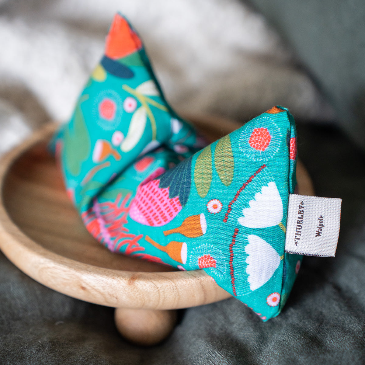 Patterned blue eye pillow, close up of design. Eye pillow resting on a wooden stand. 