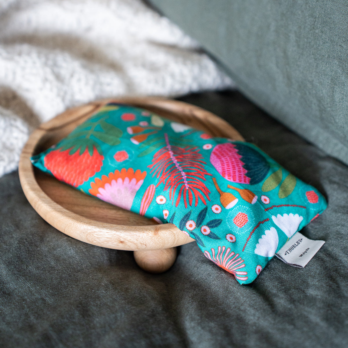 Blue floral patterned eye pillow resting on a wooden stand