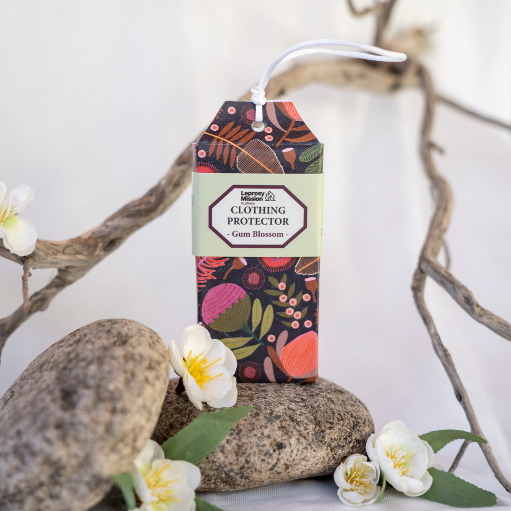Box of clothing protector with floral design on a white background with rocks and flowers.
