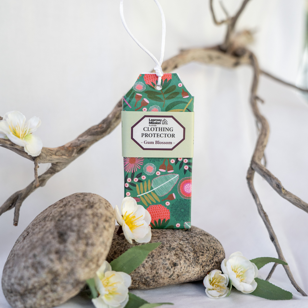 Clothing protector tag with floral design on a white background with stones and flowers.