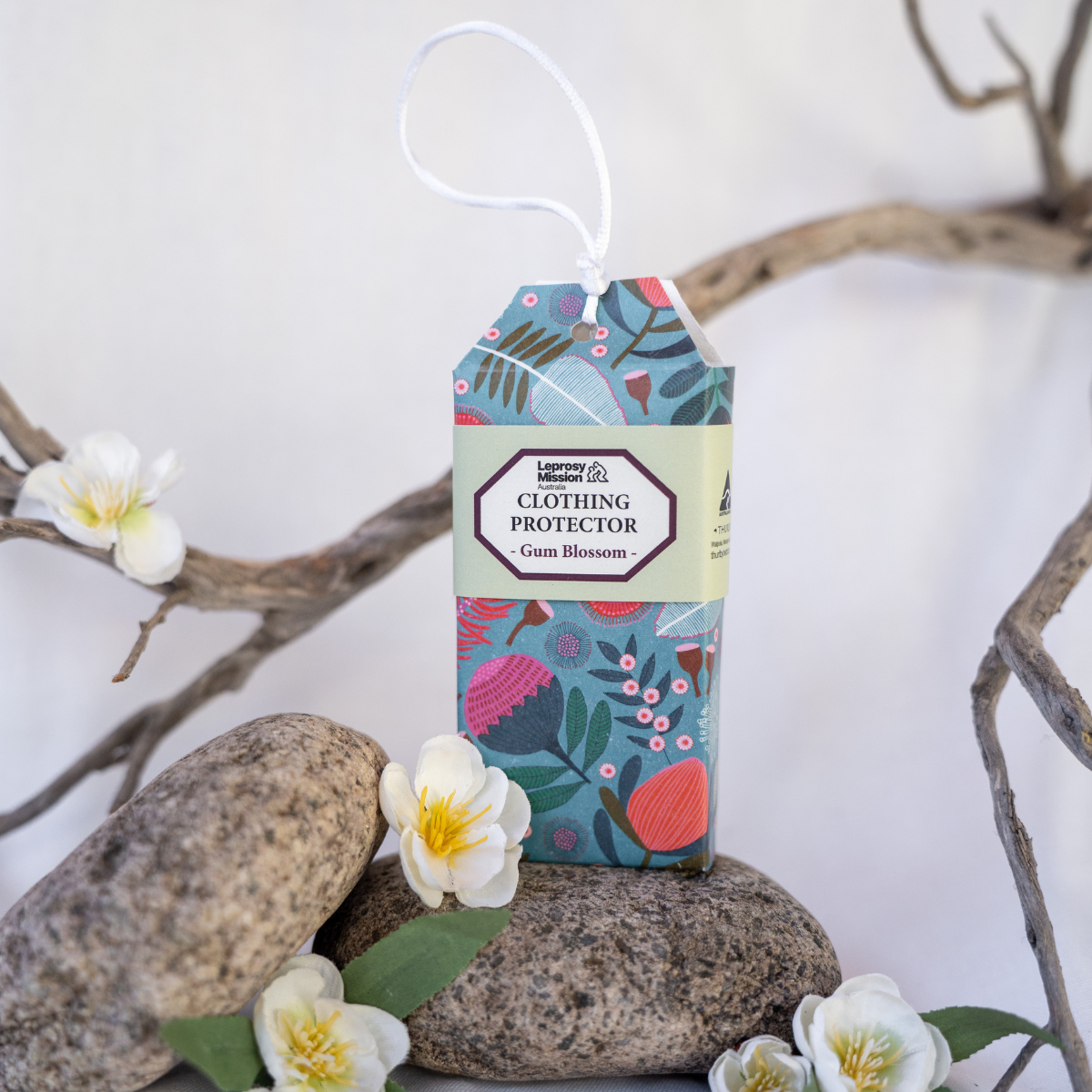 Clothing protector packaging with floral design on a white background with stones and flowers.