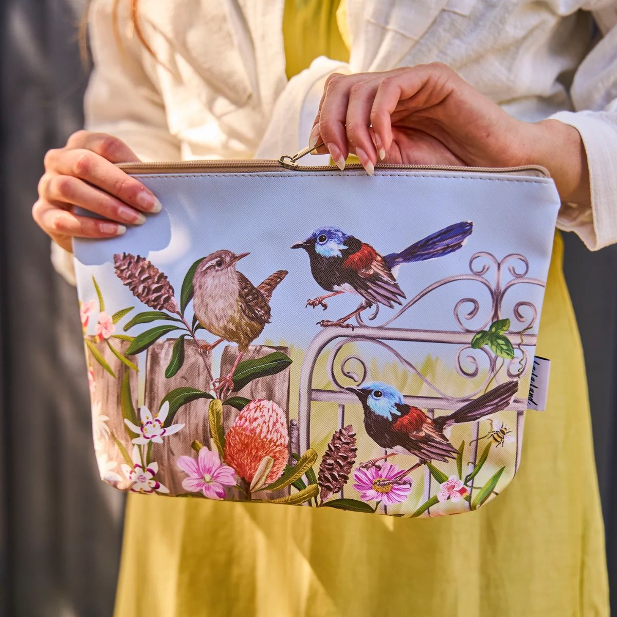 Person holding a pouch with bird and floral design