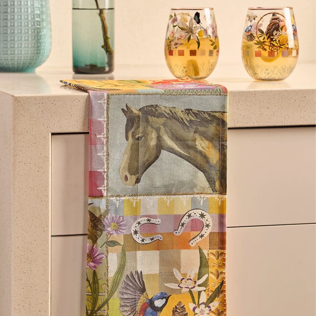 Decorative table runner with horse and floral design on a kitchen counter.