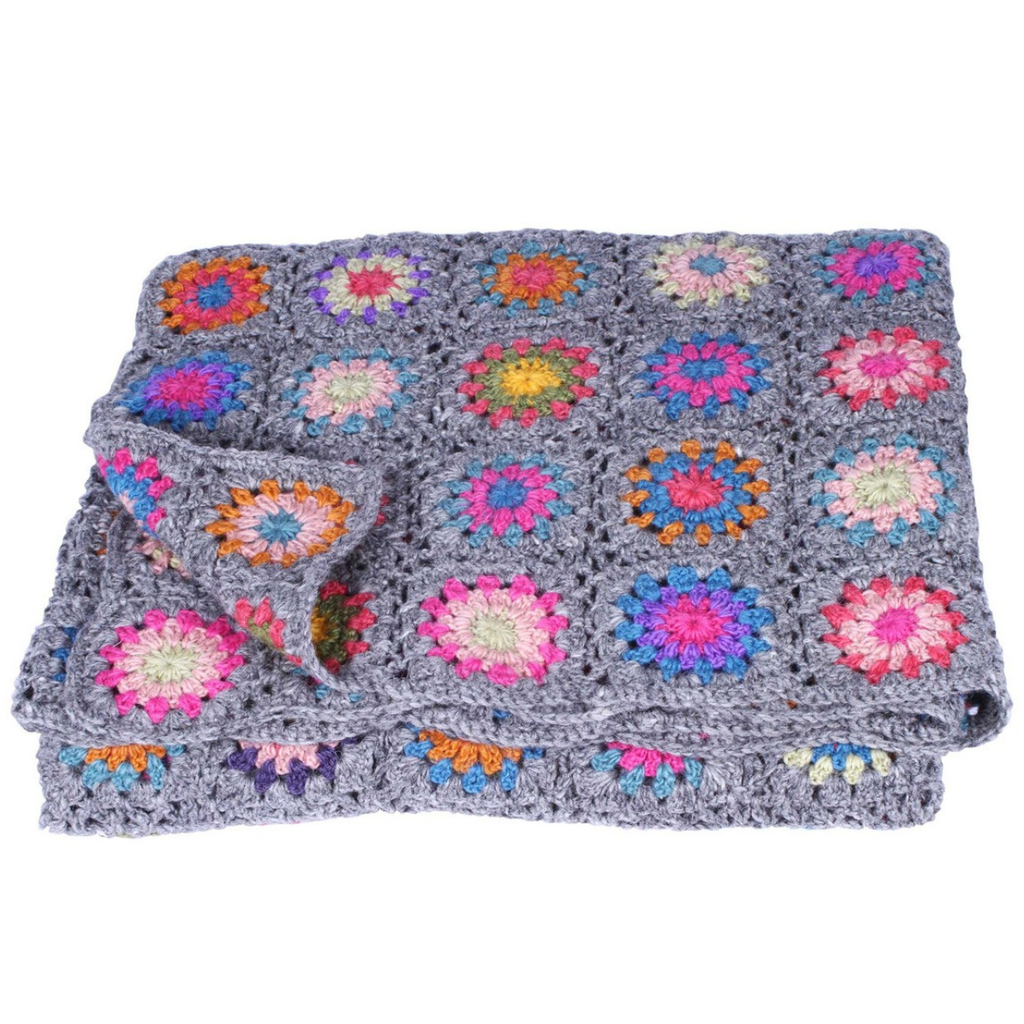 A folded gray crocheted blanket featuring colorful granny square patches in pink, blue, orange, yellow, and green, displayed on a solid white background.