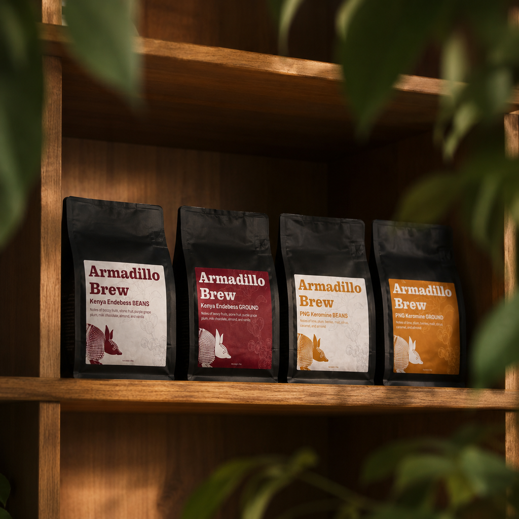 Four 'Ardillo Brew' coffee packages on a wooden shelf with plants in the foreground and background.