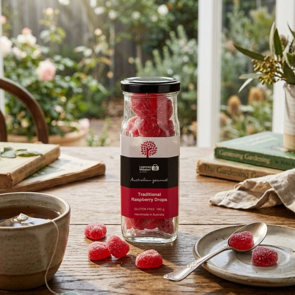 Jar of raspberry drops on a table with tea and snacks, garden view in the background