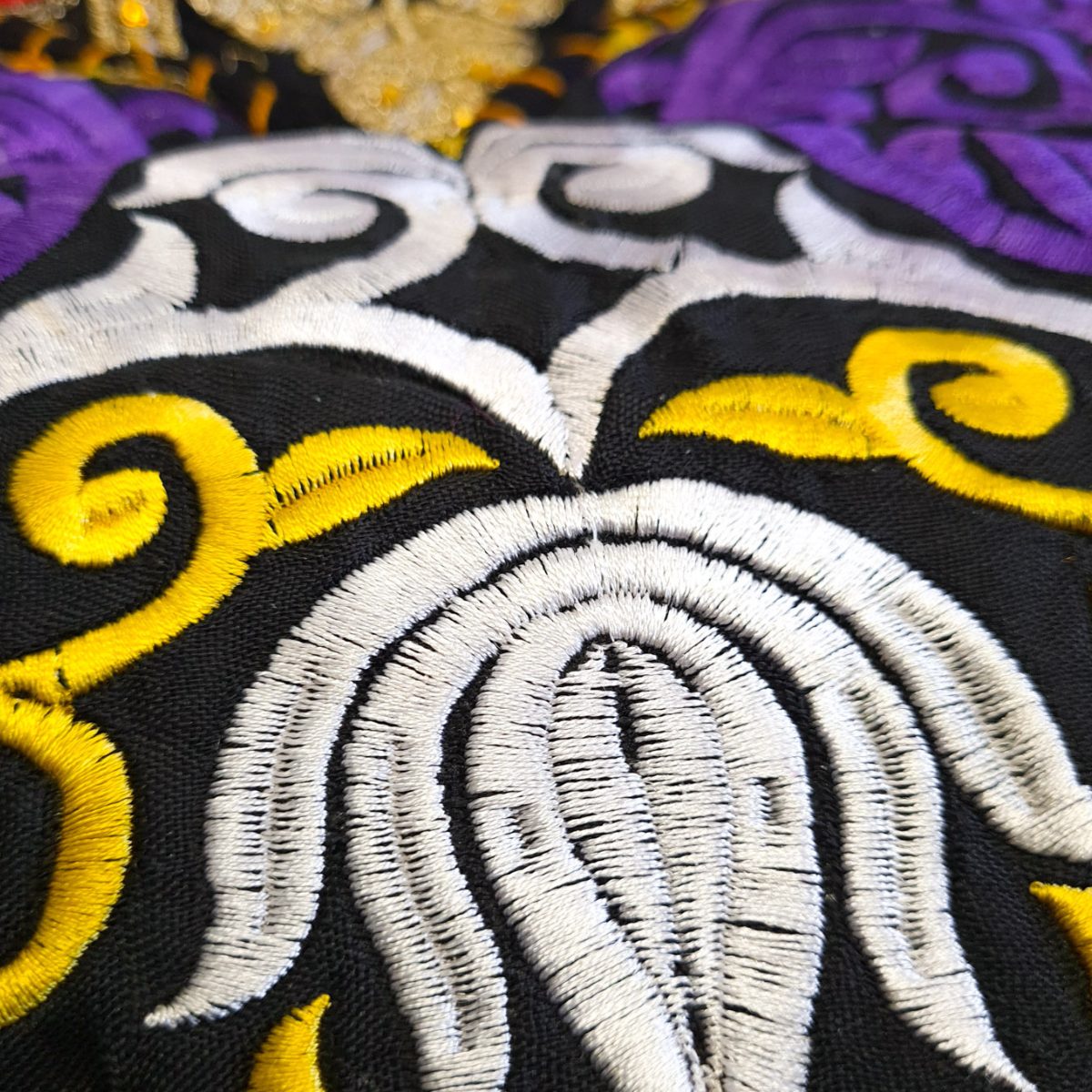 Close-up of embroidered fabric with white and yellow patterns on a black background
