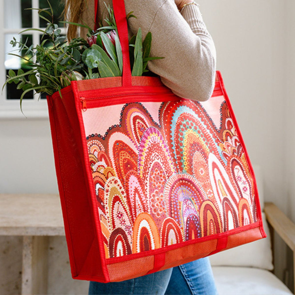 Person holding a colorful tote bag with plant and pattern