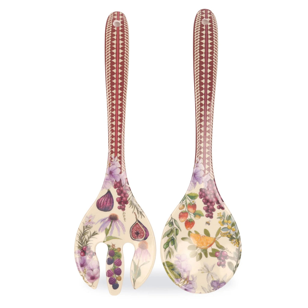 Two decorative serving utensils with long handles and broad flat heads, shown on a plain white background. The utensils have a cream base with botanical illustrations including figs, grapes, strawberries, and purple flowers, plus a reddish-brown geometric pattern near the top of each handle.