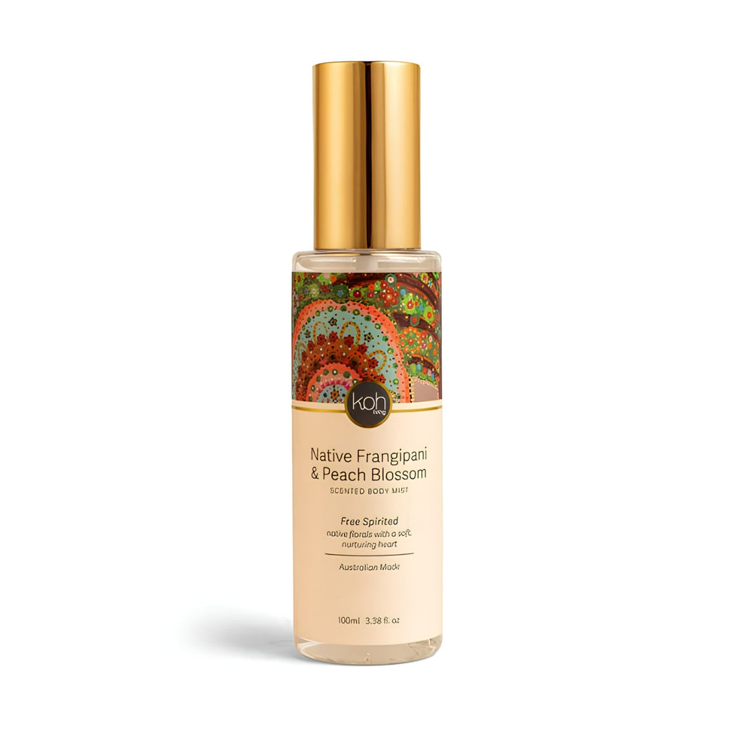 A 100ml bottle of KOH Native Frangipani & Peach Blossom Scented Body Mist. The bottle is clear glass showing a light peach-colored liquid inside, topped with a metallic gold cap.